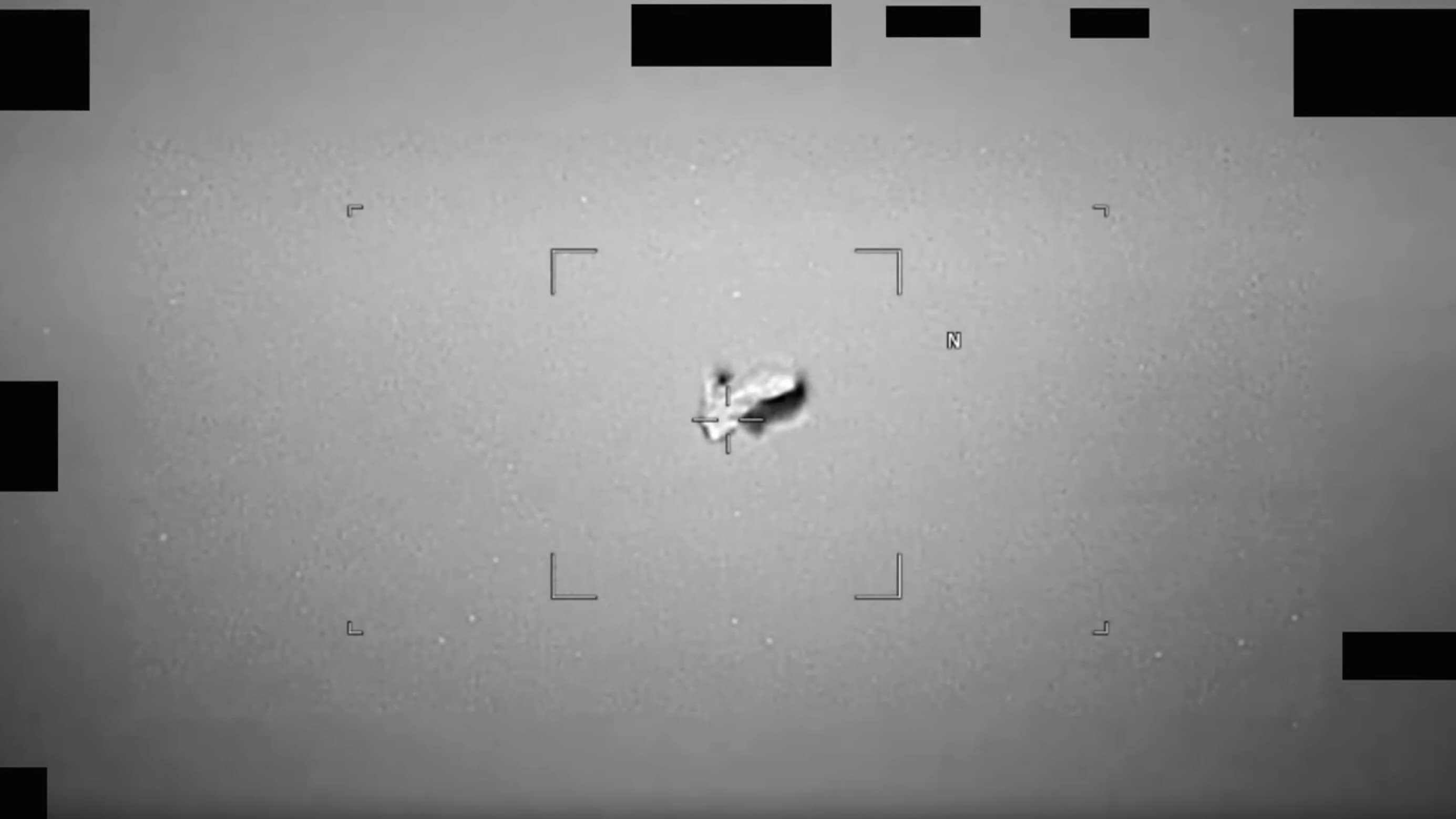 black and white photo of a blurry, football-shaped object in the sky