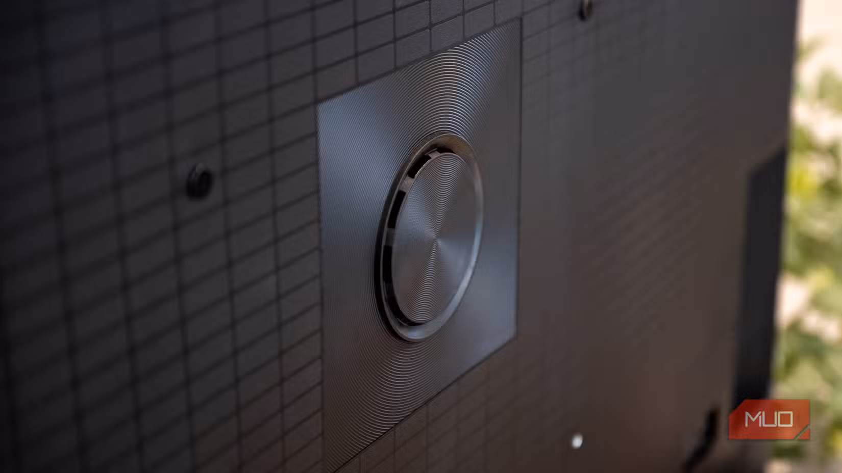 Close-up of the Hisense U6 Pro rear speaker driver centered on the textured grid back panel with mounting screws visible.