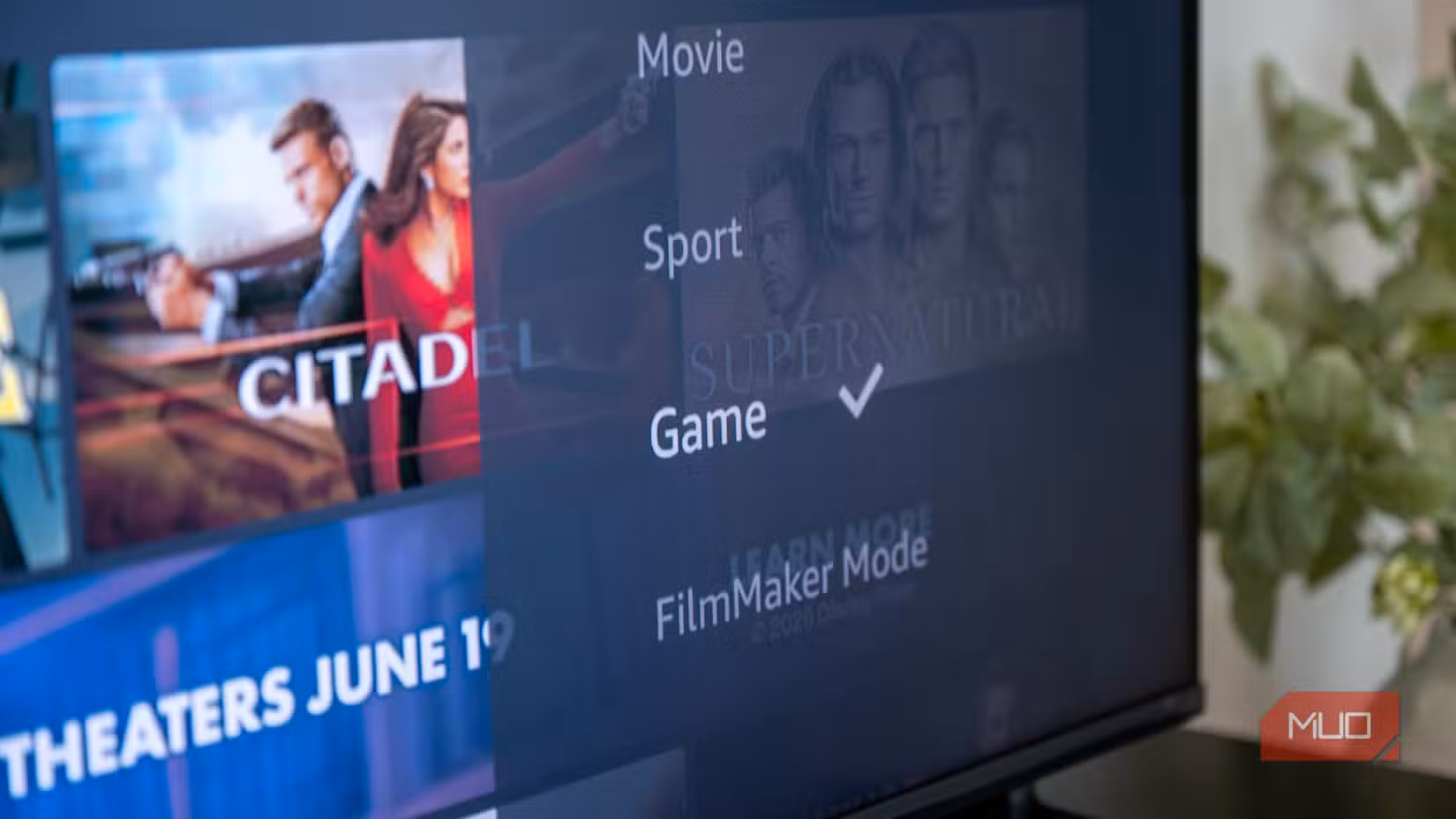 The Hisense U6SF Pro displaying the Fire TV picture mode selection menu with Game mode selected, viewed from the side with a plant in the background.