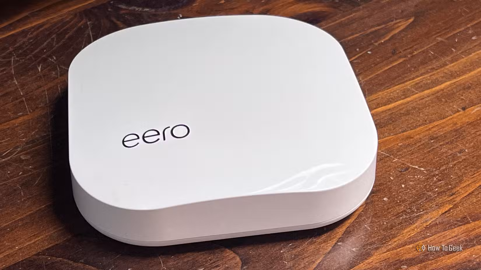 An image of a white eero Mesh Wi-Fi router on a walnut tabletop.