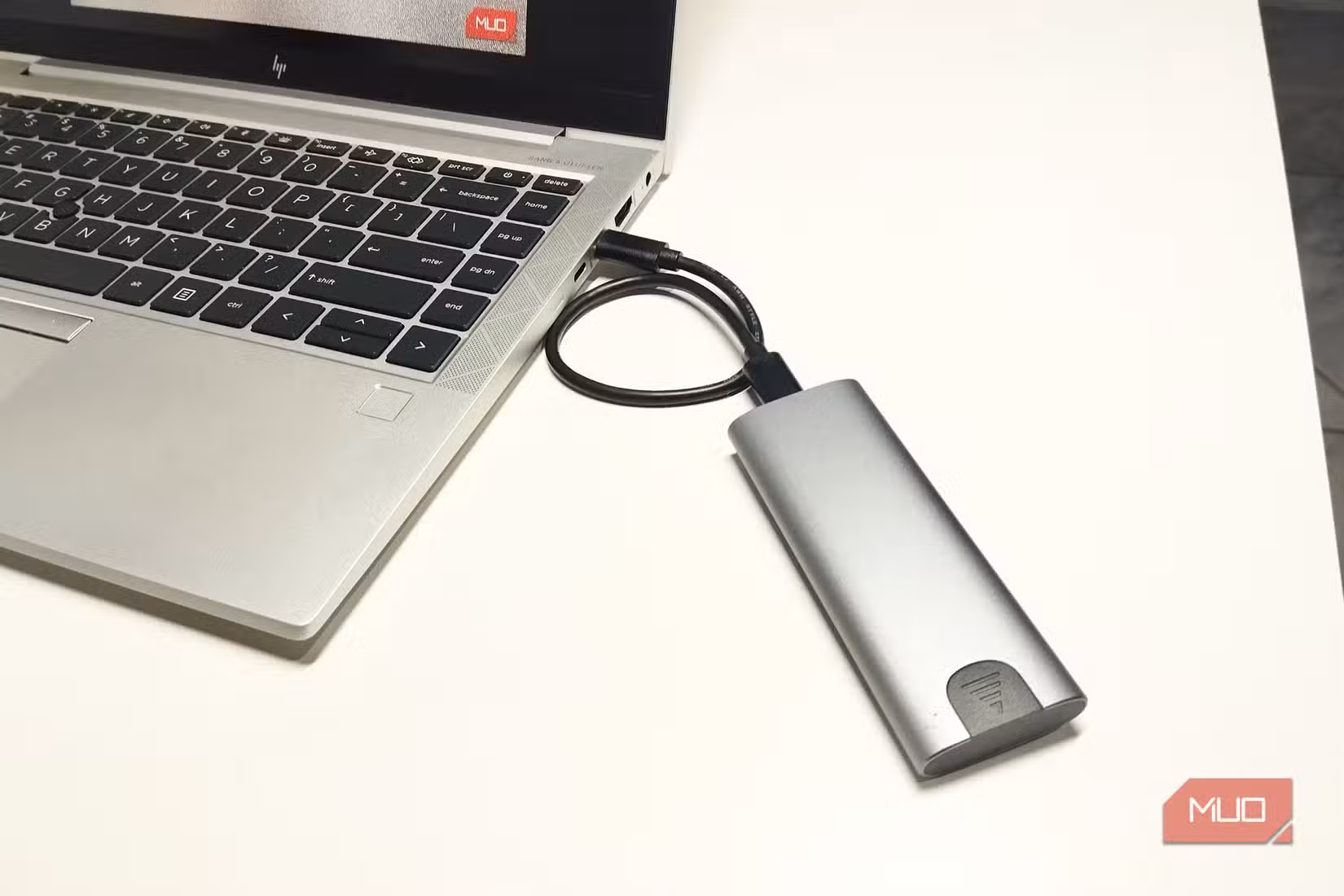 An external NVMe SSD enclosure connected to a laptop via Thunderbolt.