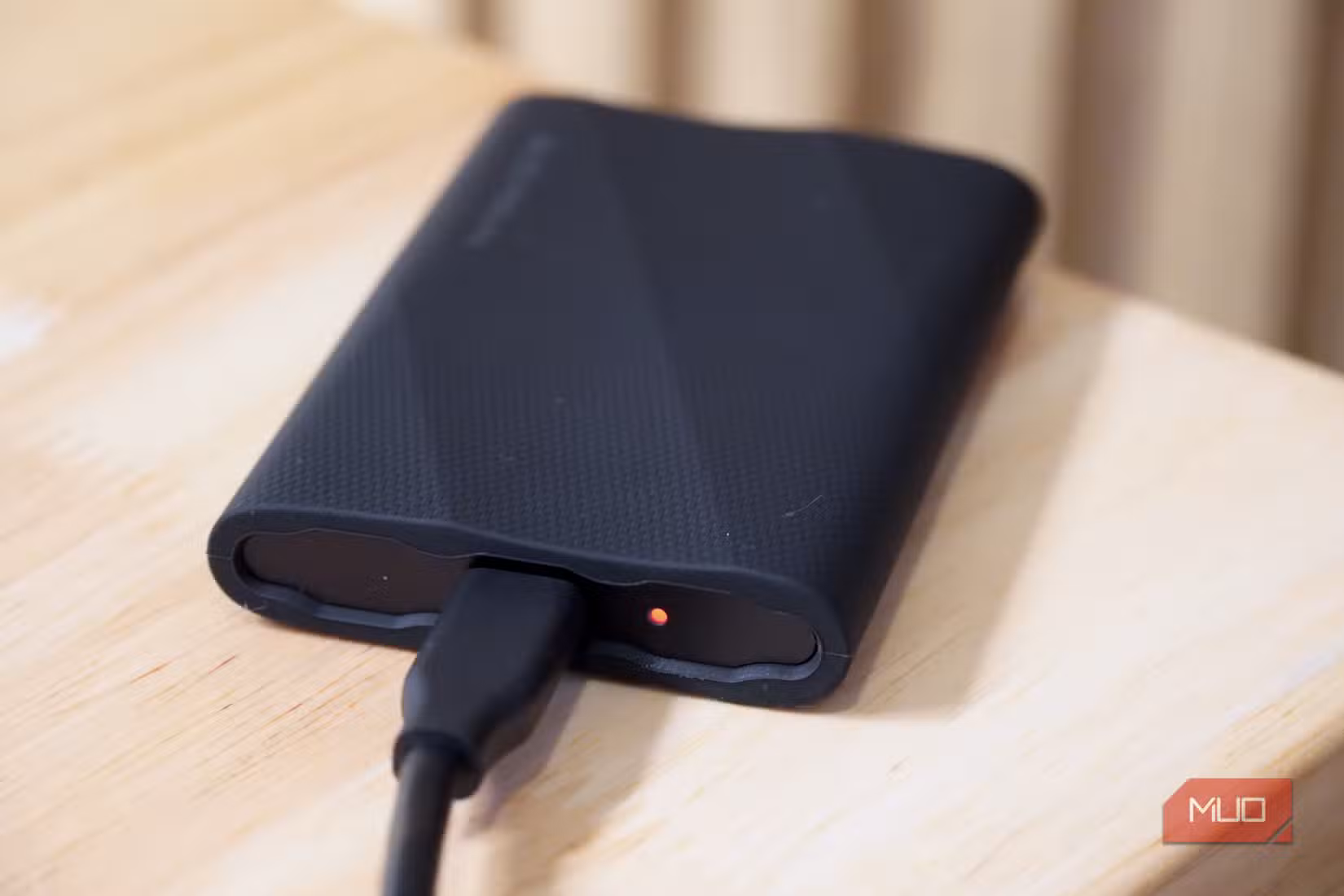 A Samsung T9 Portable SSD transferring data with the LED status light orange.