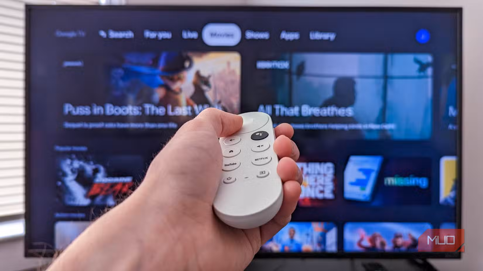 Person holding a Chromecast remote infront of a tv with Google TV open