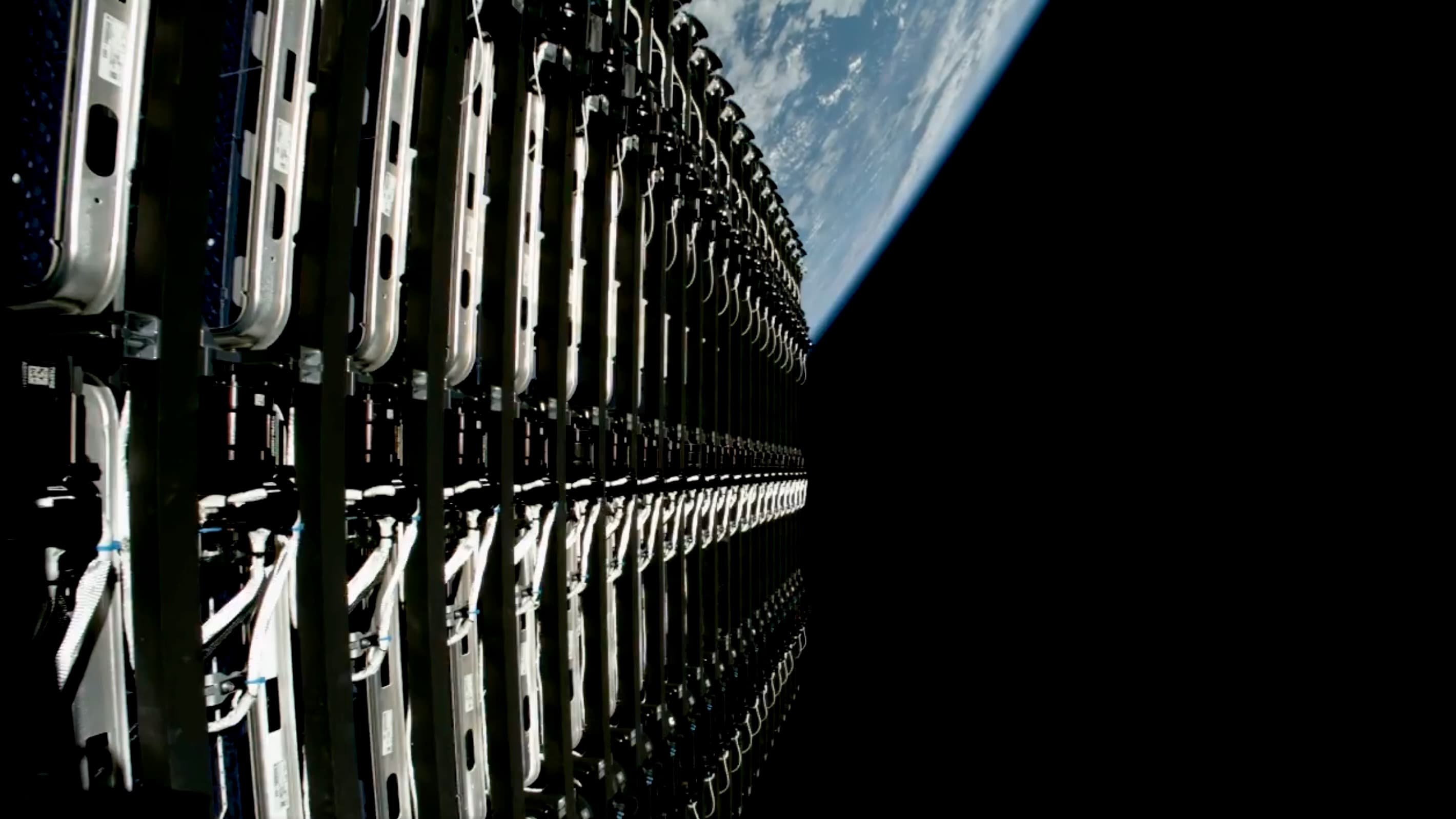 closeup view of 24 flat starlink satellites in space, before they're deployed, with earth in the background