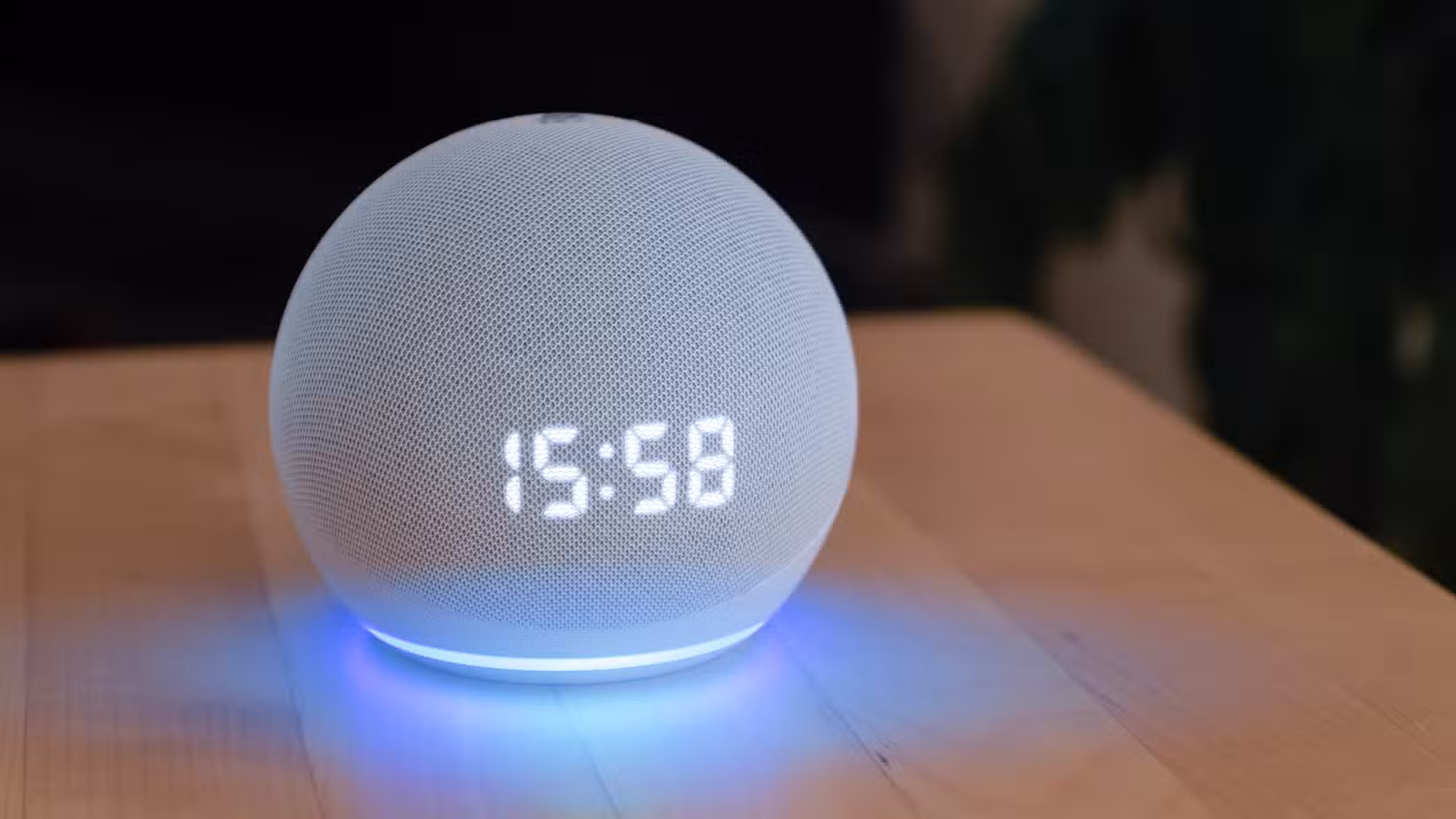 An Echo Dot on a table with the time displayed on it and the ring glowing.