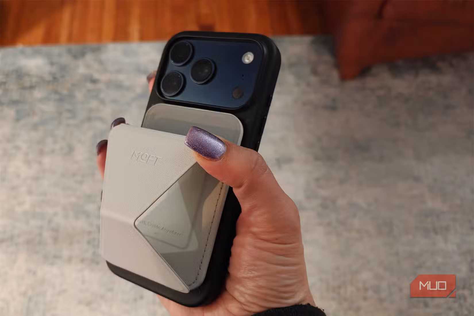 A hand holding an iPhone with the Moft Wallet Stand on the back.