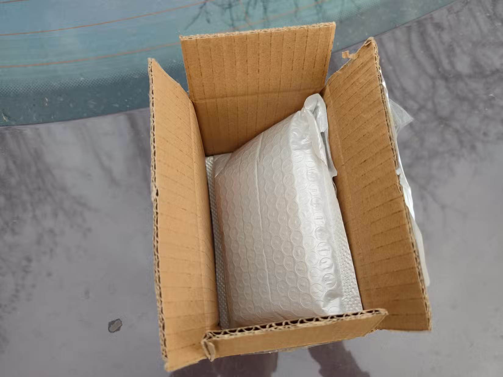A white bubble wrap package containing a CPU inside of a brown cardboard box.