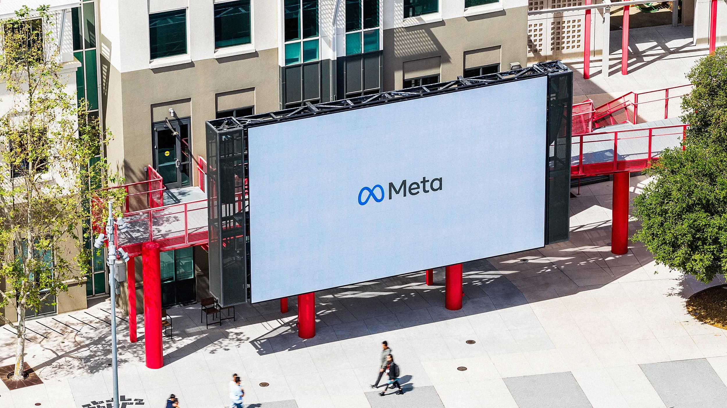 Workers walk past a display at Meta headquarters on Thursday March 26 2026 in Menlo Park Calif.