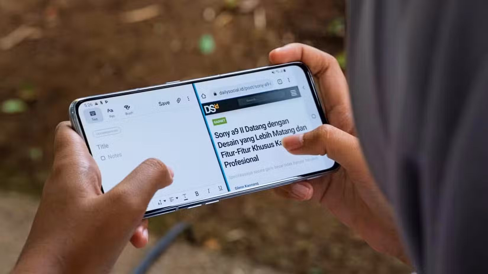 Person's hands holding an Android phone and using it in split-screen mode.