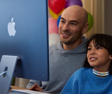 Adult and young child both engaged in content on iMac, blue