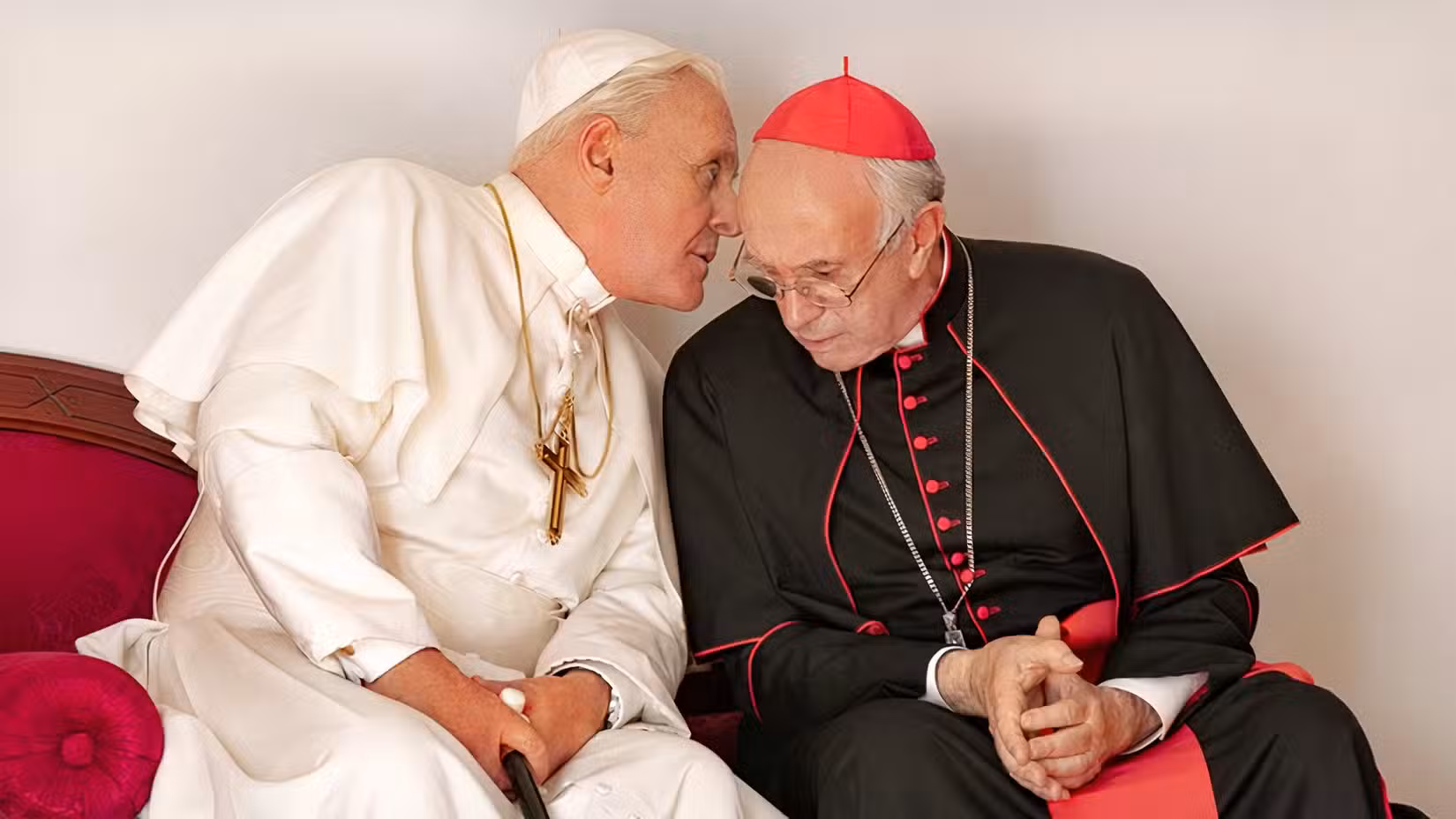 A pope whispers into a cardinal's ear in The Two Popes.