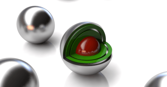 Image of a set of silvery balls, one of which has a cutaway showing layers of green and a red core.