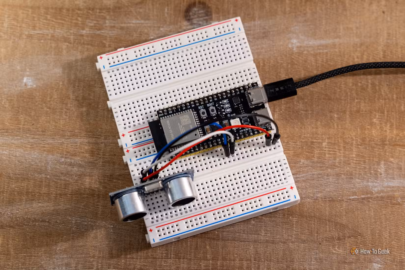 Overhead view of an ESP32 development board connected to an HC-SR04 ultrasonic sensor on a breadboard.