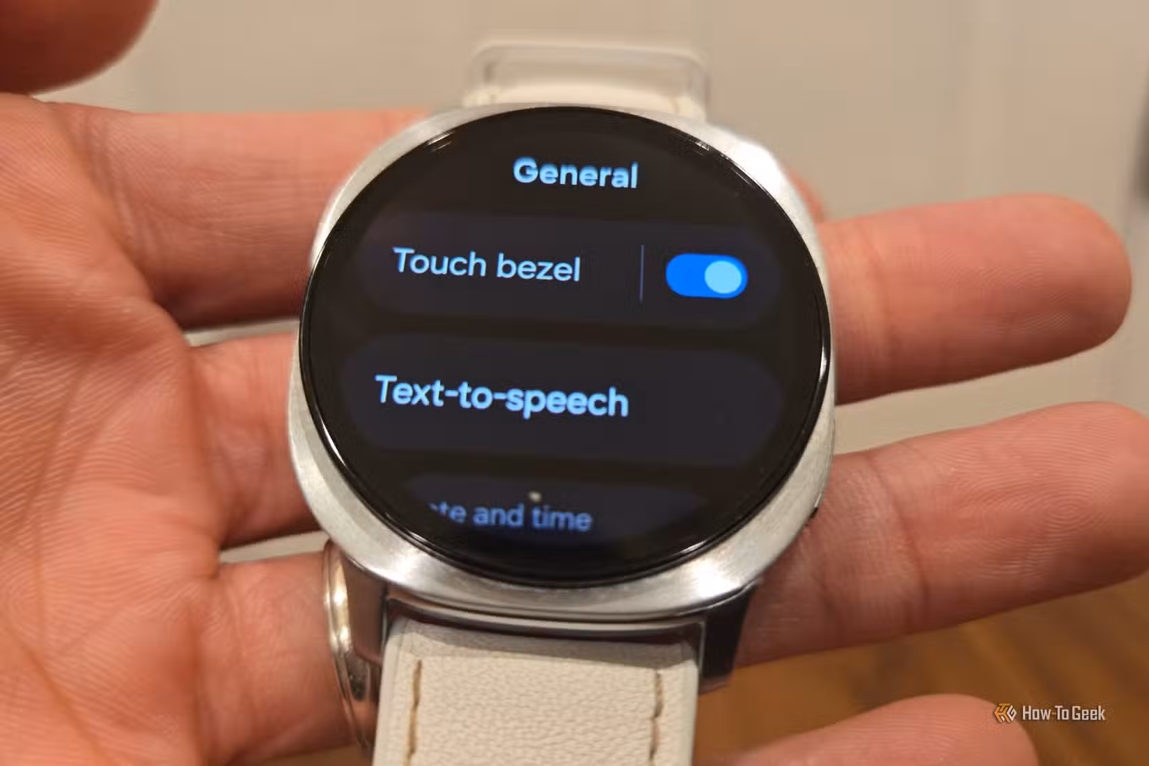 Hand holding a Samsung Galaxy Watch 8 showing the Touch Bezel setting