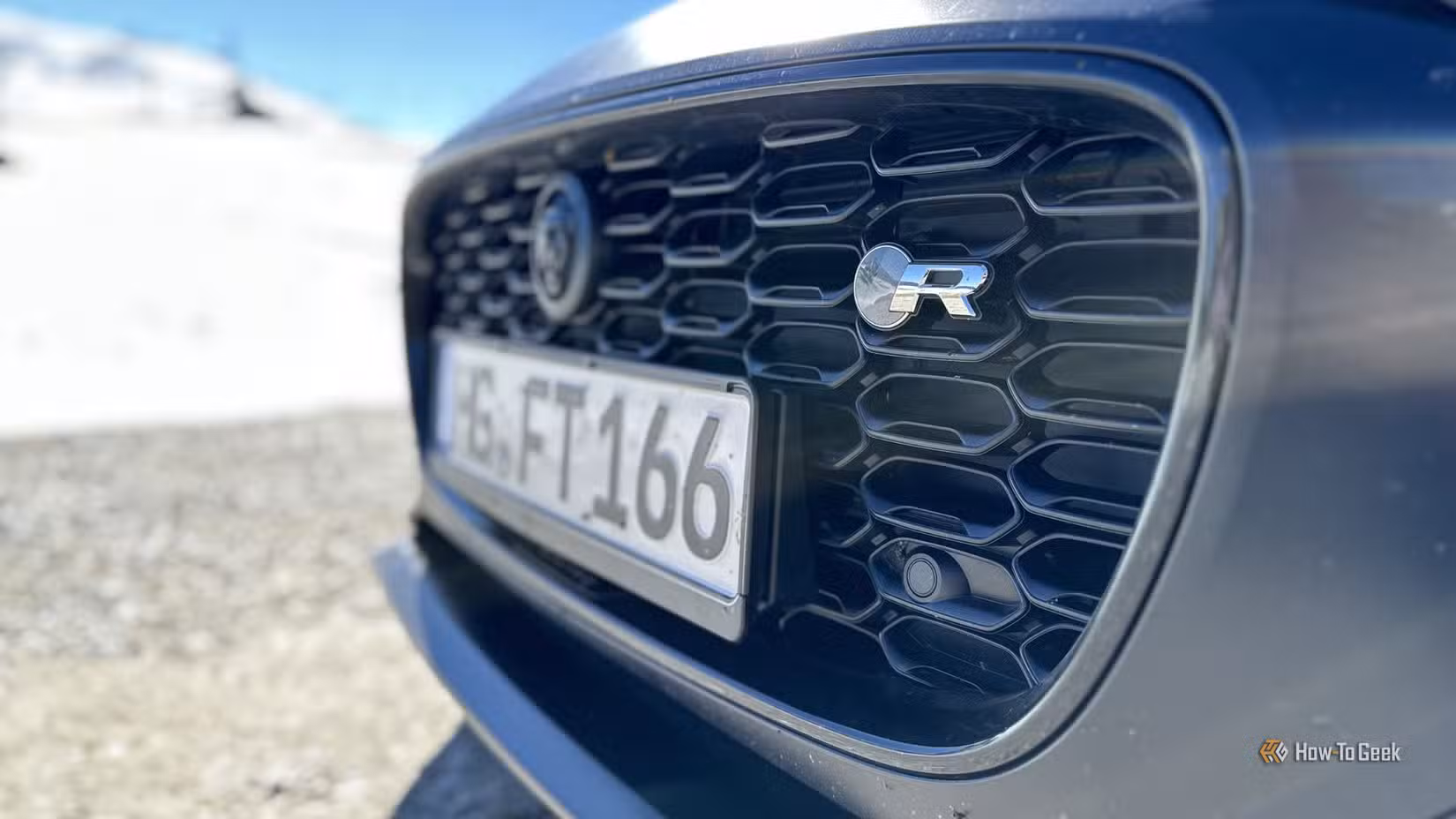 Close-up shot of the badging on the front grille of a black 2023 Jaguar F-Type R 75.