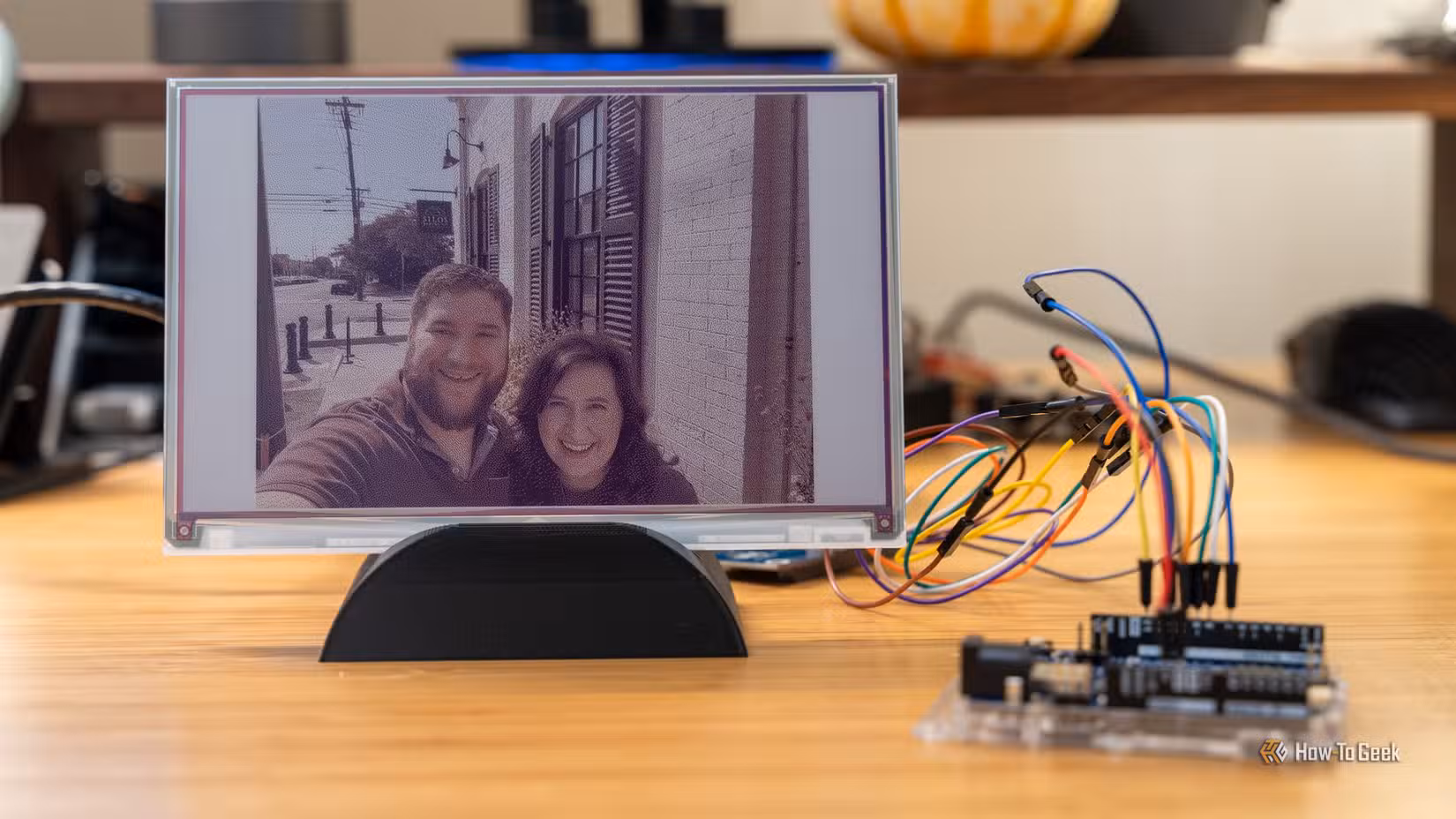 A color e-ink display on a 3D printed stand with an Arduino in the foreground.
