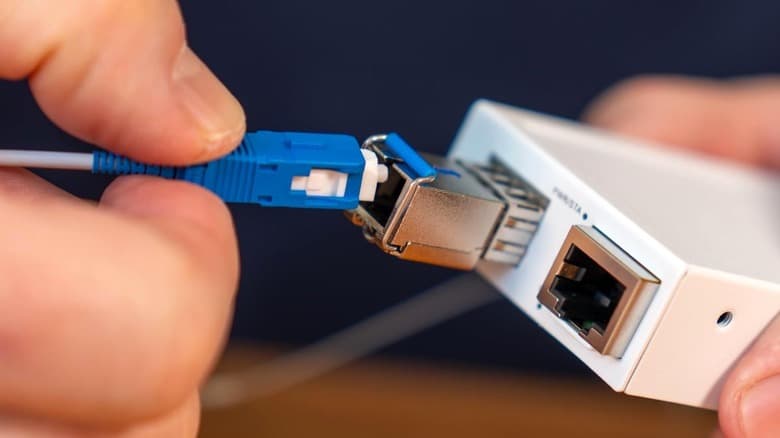 Photo, close-up, of a hand plugging in a fiber optic cable from an InvisiLight Home Fiber Kit