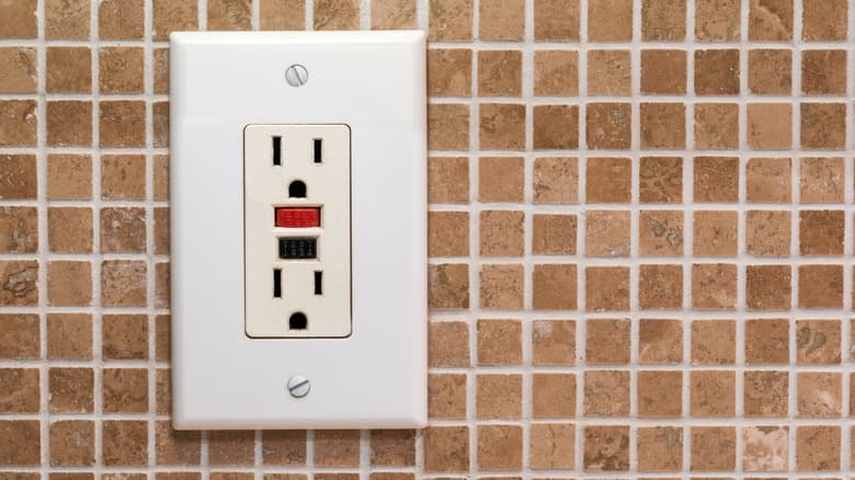 Photo of a white A/C outlet installed on a wall of small, square tan tiles.