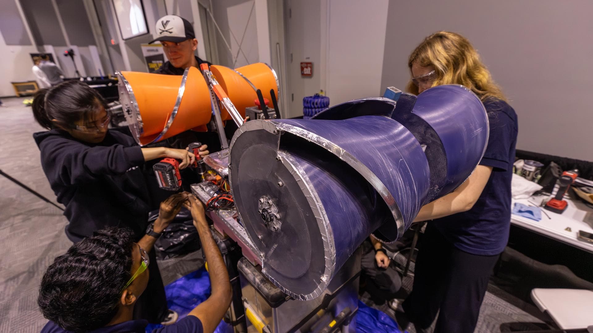 College students work on an excavating robot with orange and blue digger drums