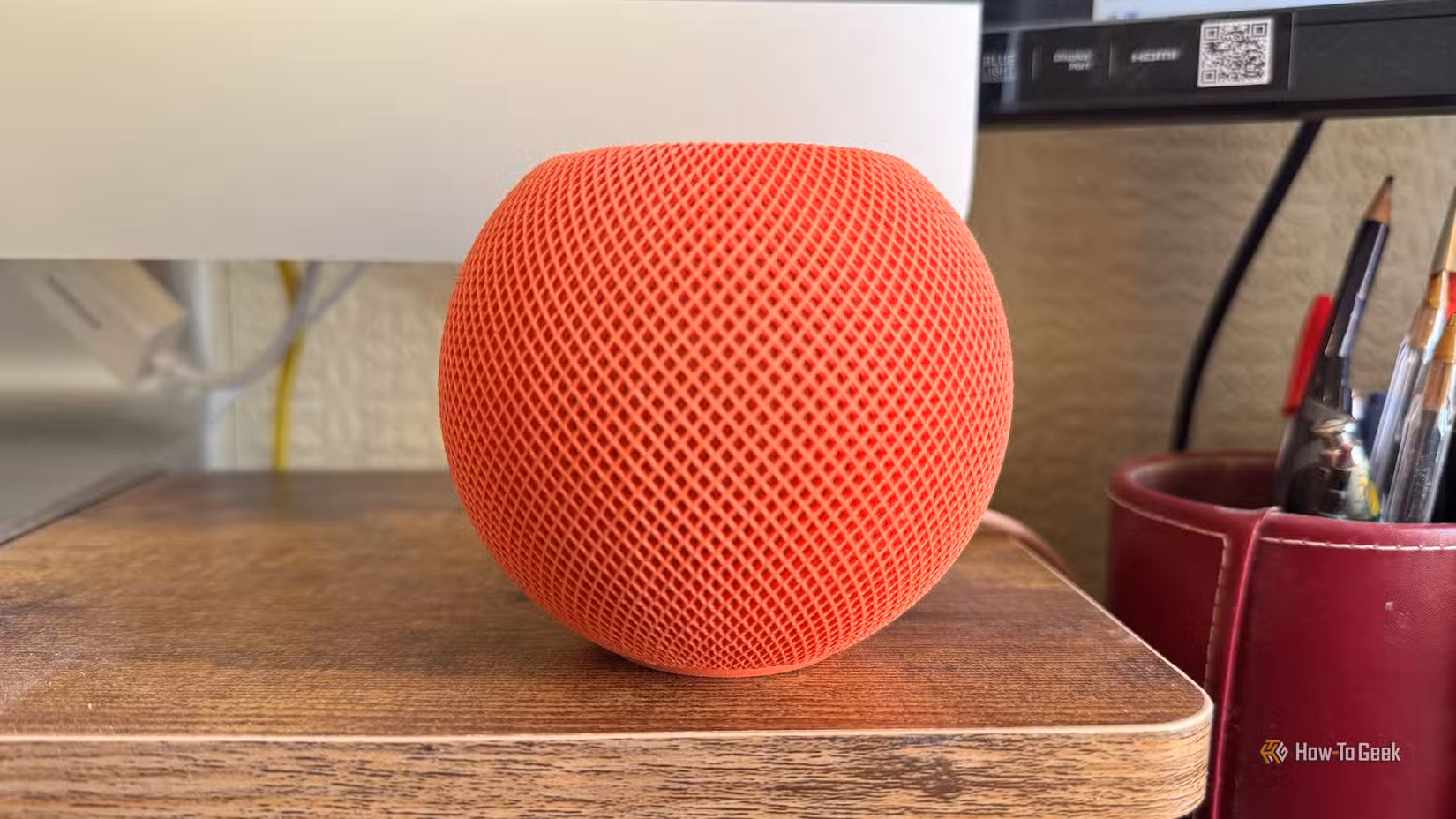 An Apple HomePod mini in front of an iMac screen.