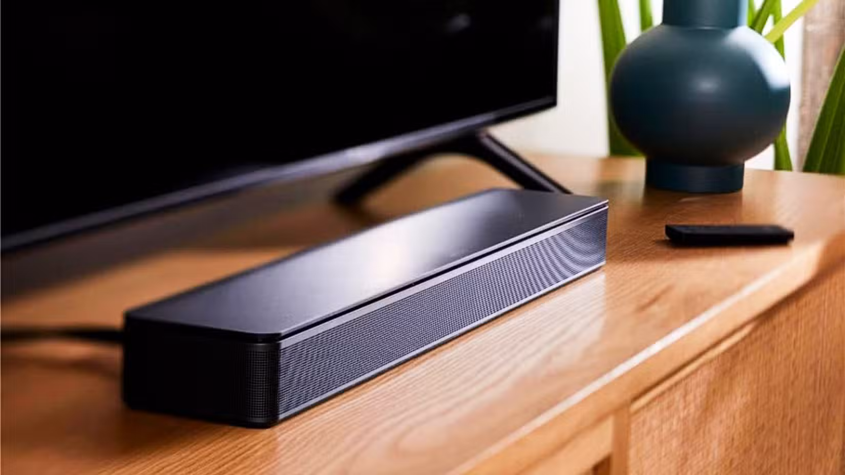 Bose TV Speaker Soundbar on a TV stand near a TV.