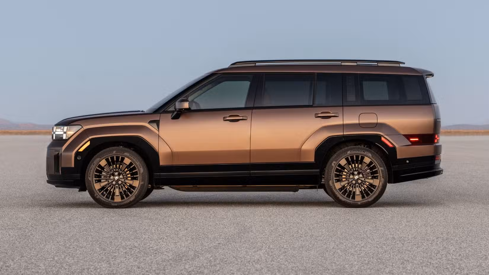 Static side profile shot of a bronze 2025 Hyundai Santa Fe Hybrid parked on a salt plain.