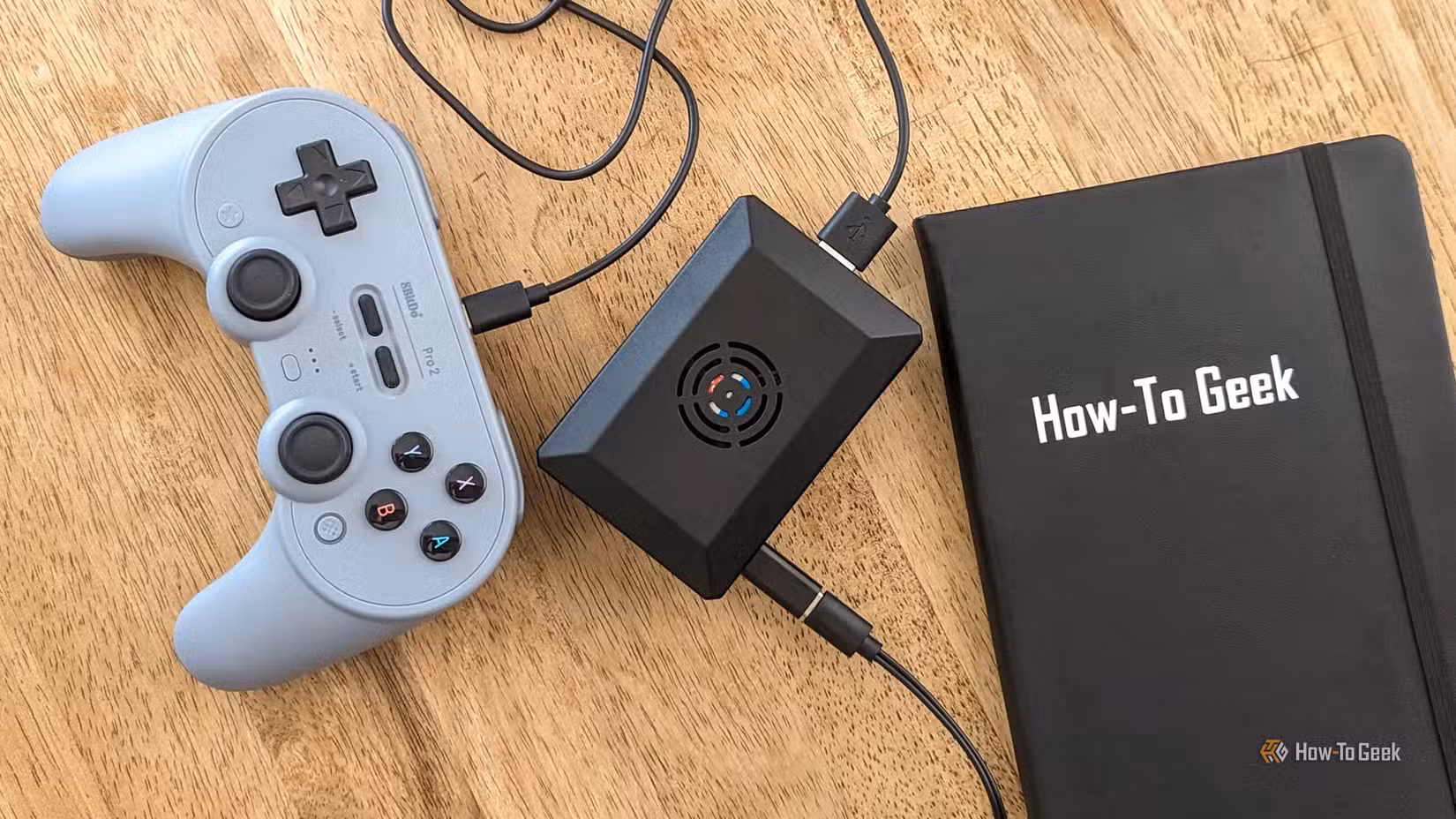 A Raspberry Pi connected to a gamepad, plus a How-To Geek notebook.