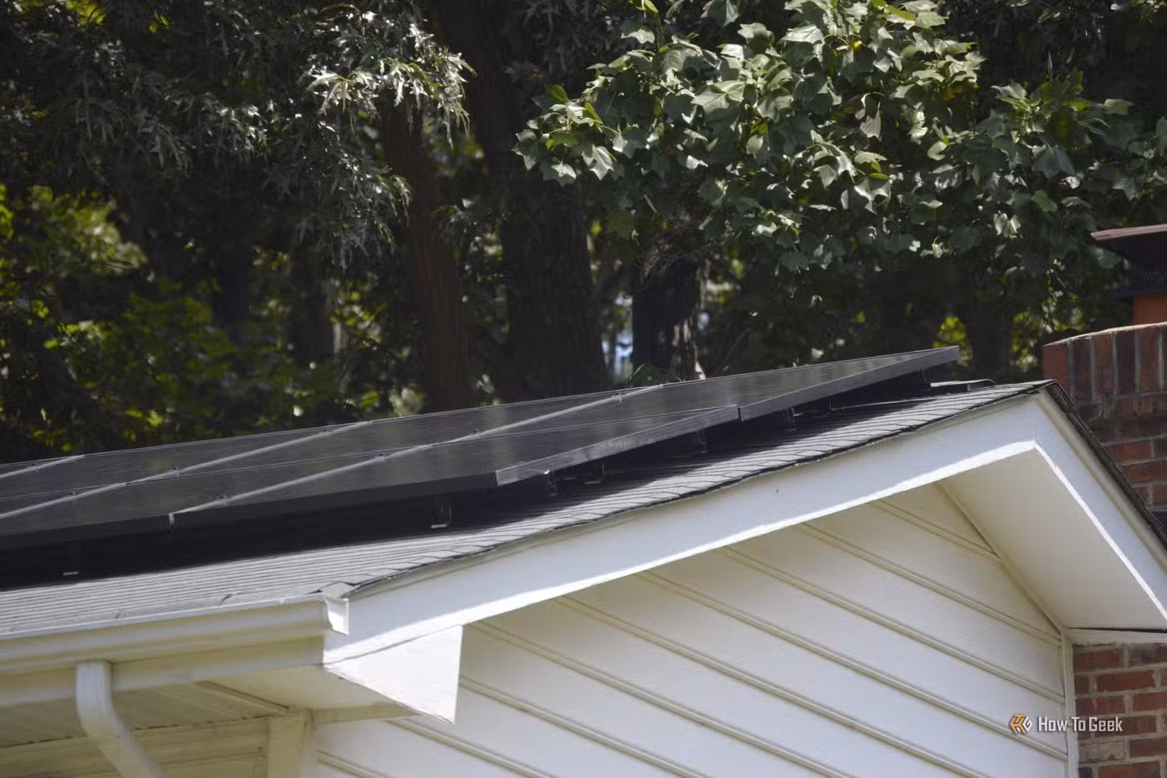 Closeup of solar panels on the roof of a white house.