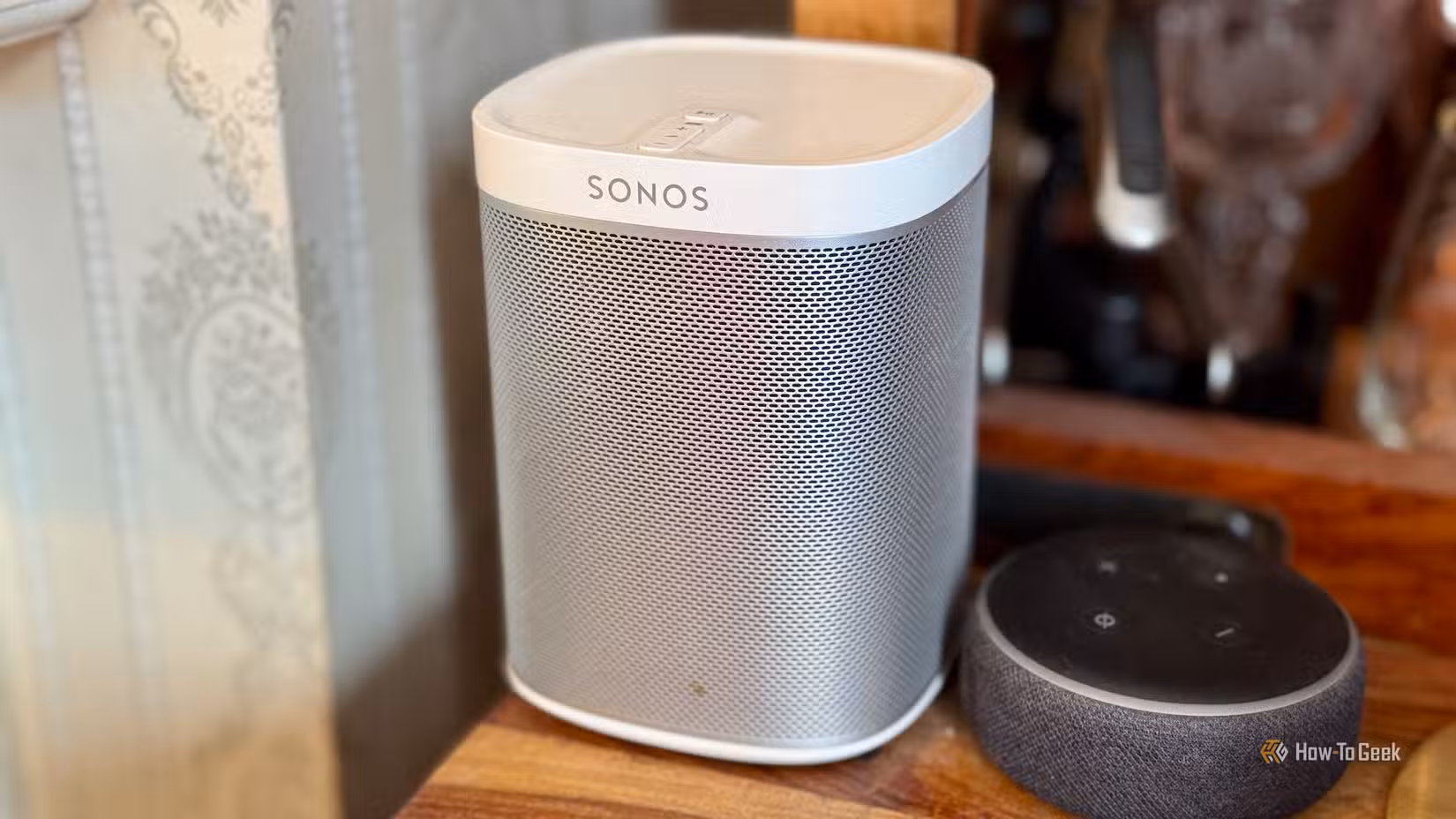 A Sonos speaker next to an Amazon Echo Dot on a cabinet.