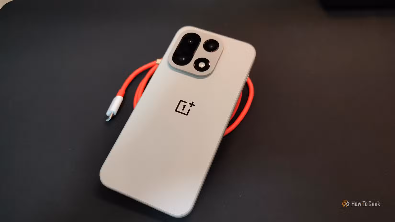 The OnePlus 15 resting against a red cable.