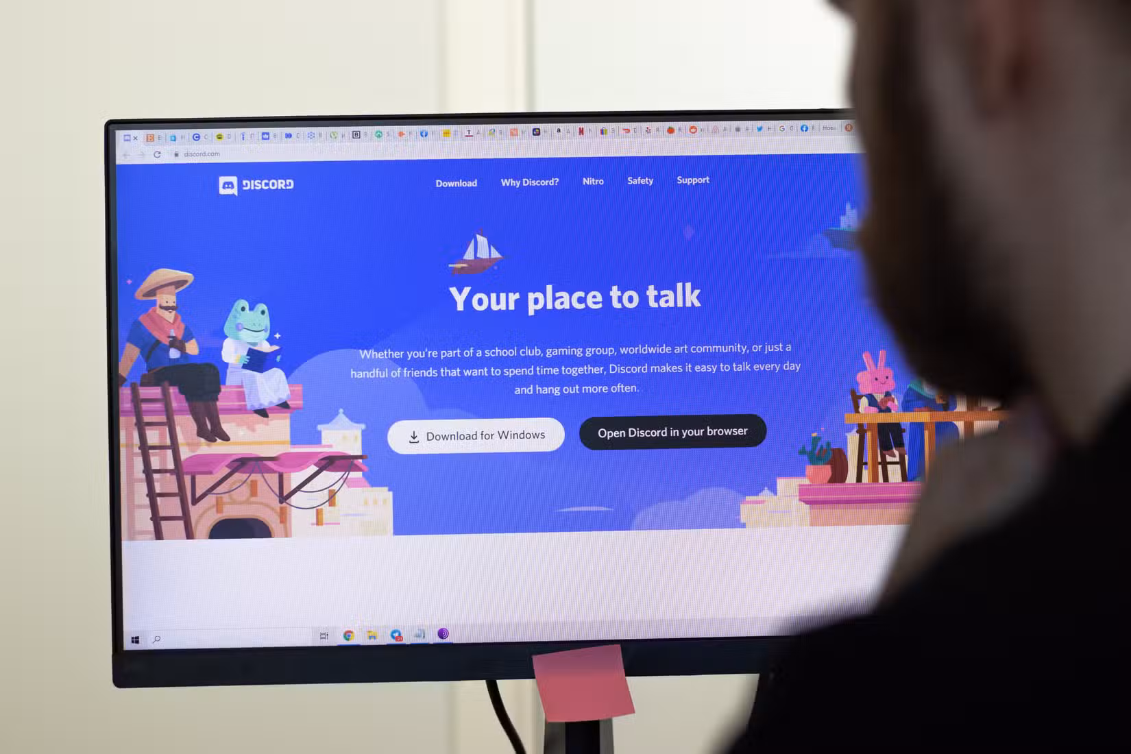 An image of the Discord website on screen. man using service.