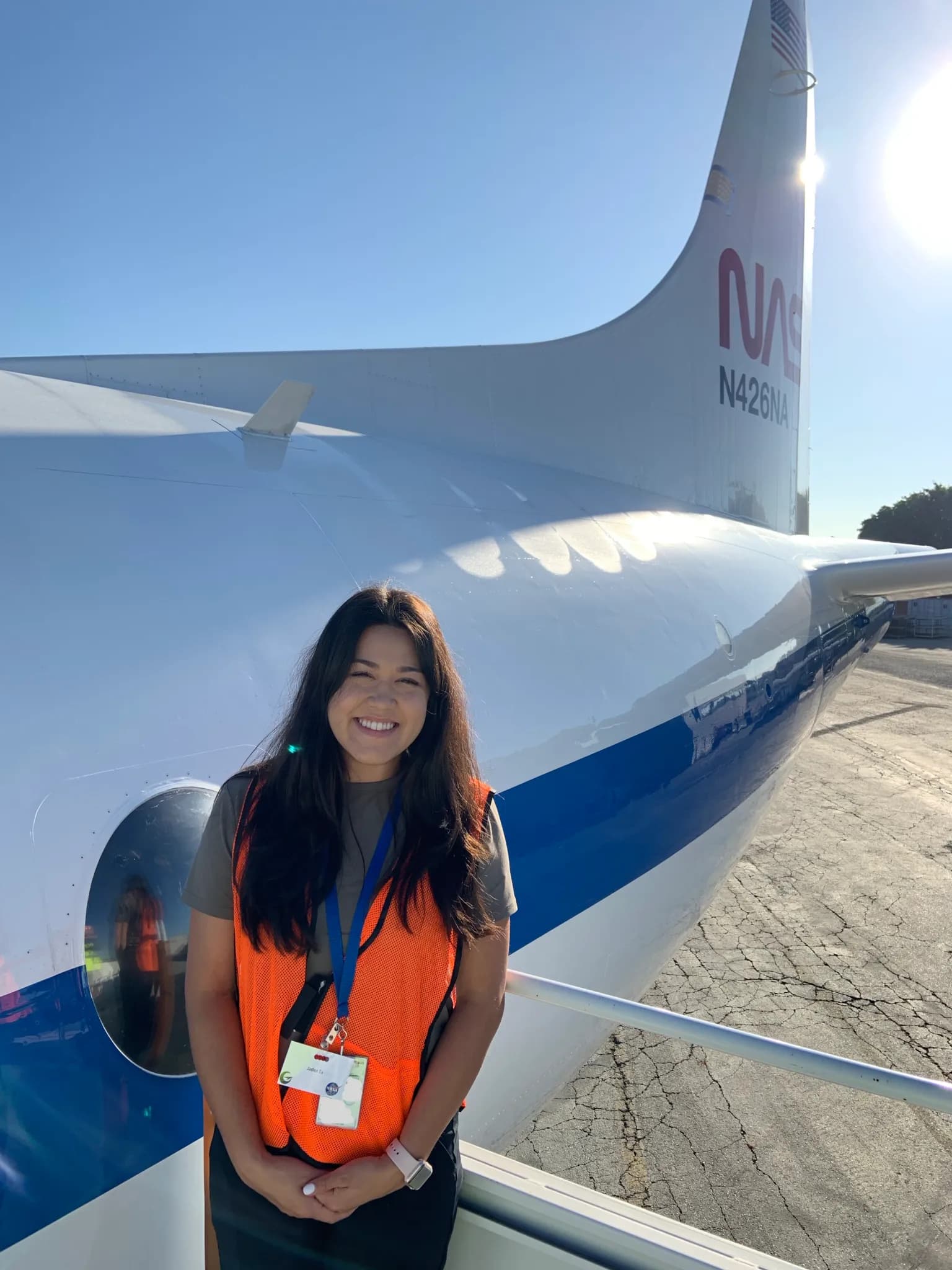 Image of NASA Ames scientist Jaden Ta wearing a safety jacket while standing in front of a NASA aircraft.