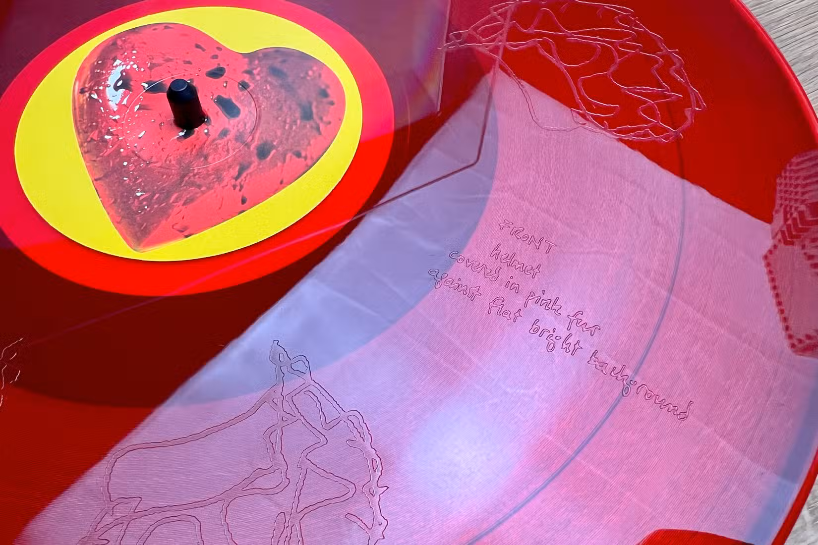 A close-up of a red Breeders vinyl records with etchings in it