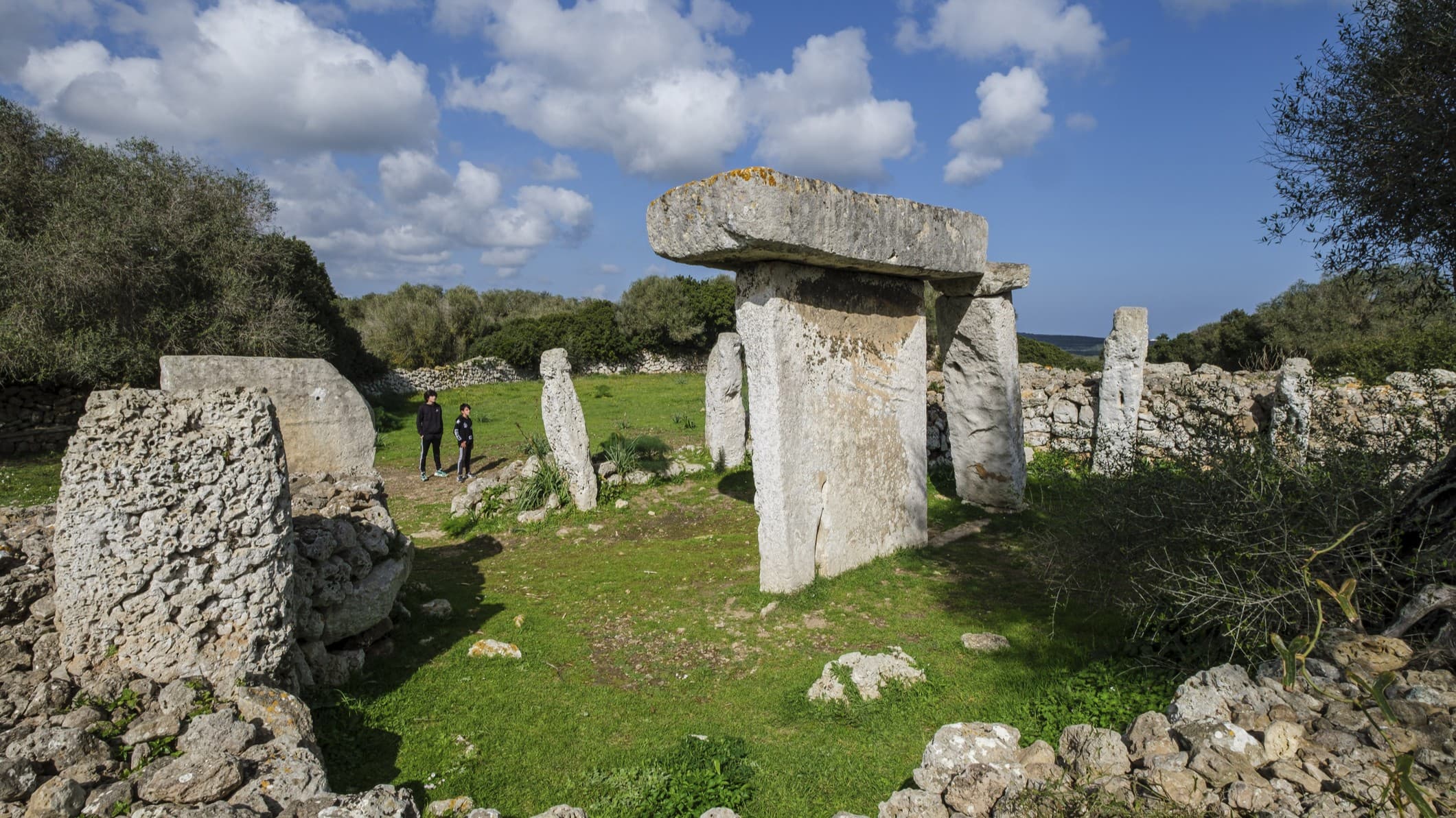 a series of large stones standing vertically under a partly cloudy sky.