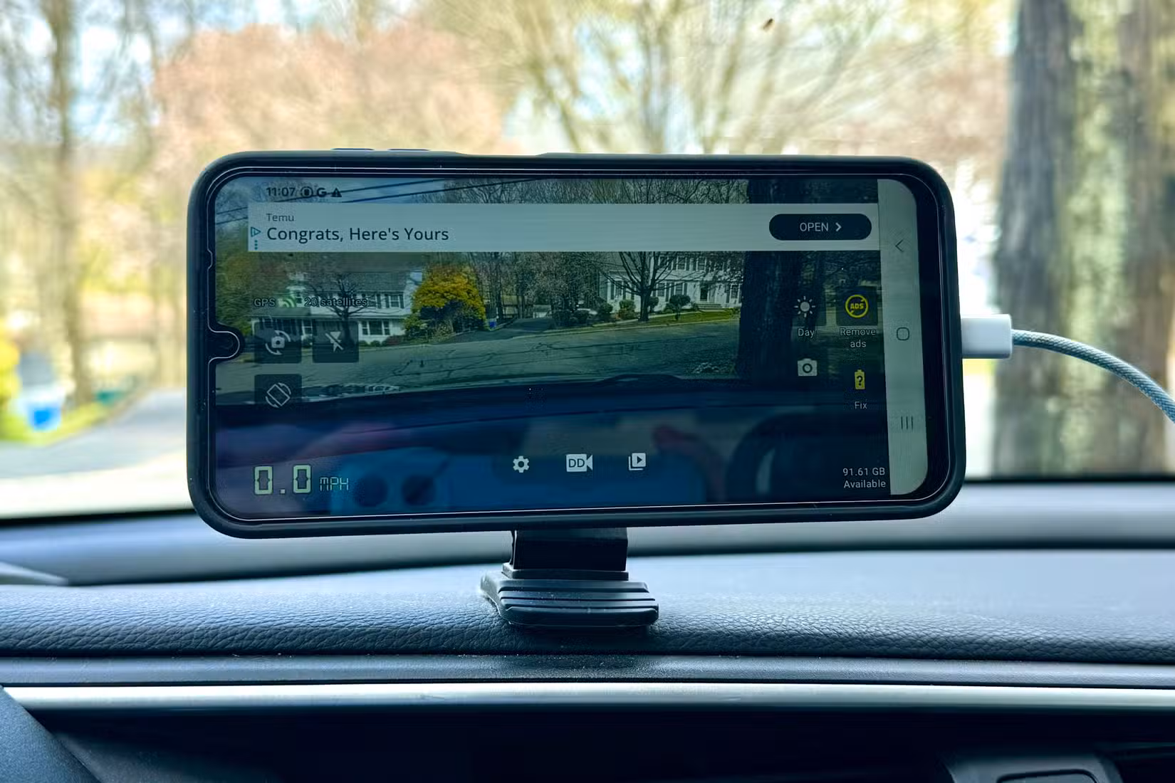 Phone magnetically attached to a mount on the dashboard in a car.