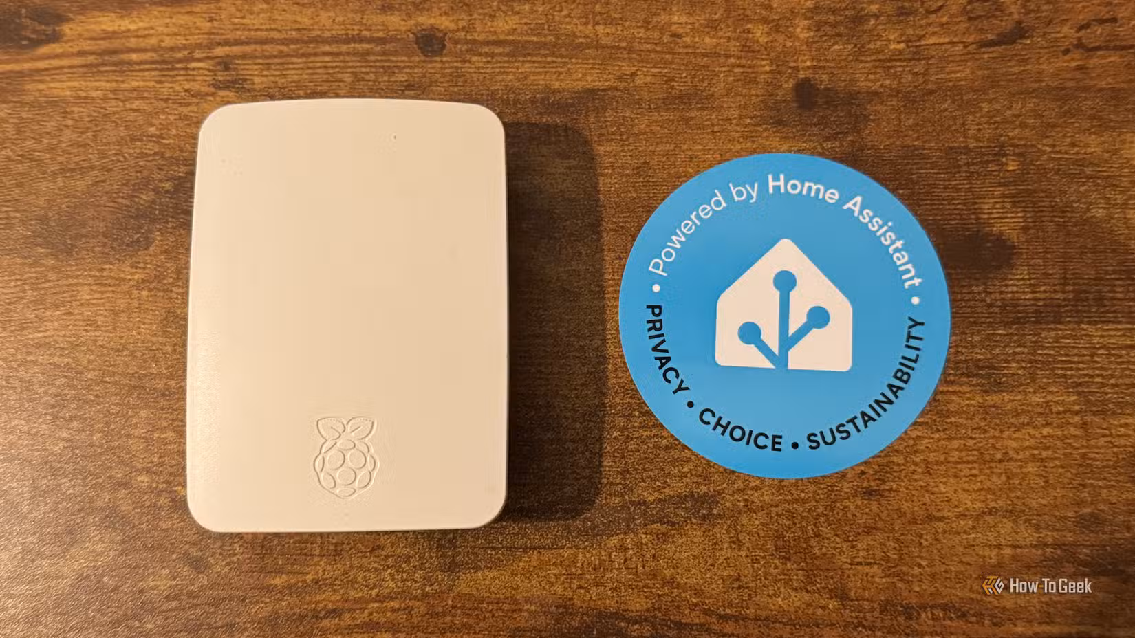 A Rasbperry Pi in an official Raspberry Pi case next to a Home Assistant sticker.