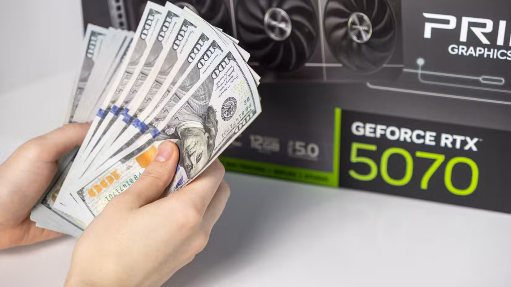 A pair of hands hold money in front of a GPU box.
