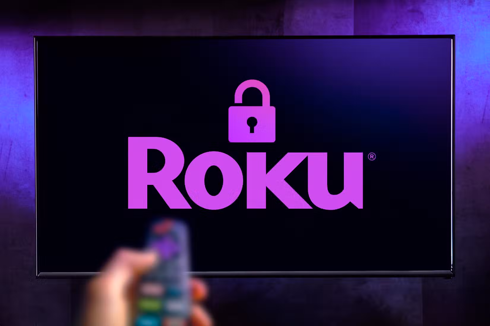 TV with the Roku logo with a padlock and a hand holding a remote control.