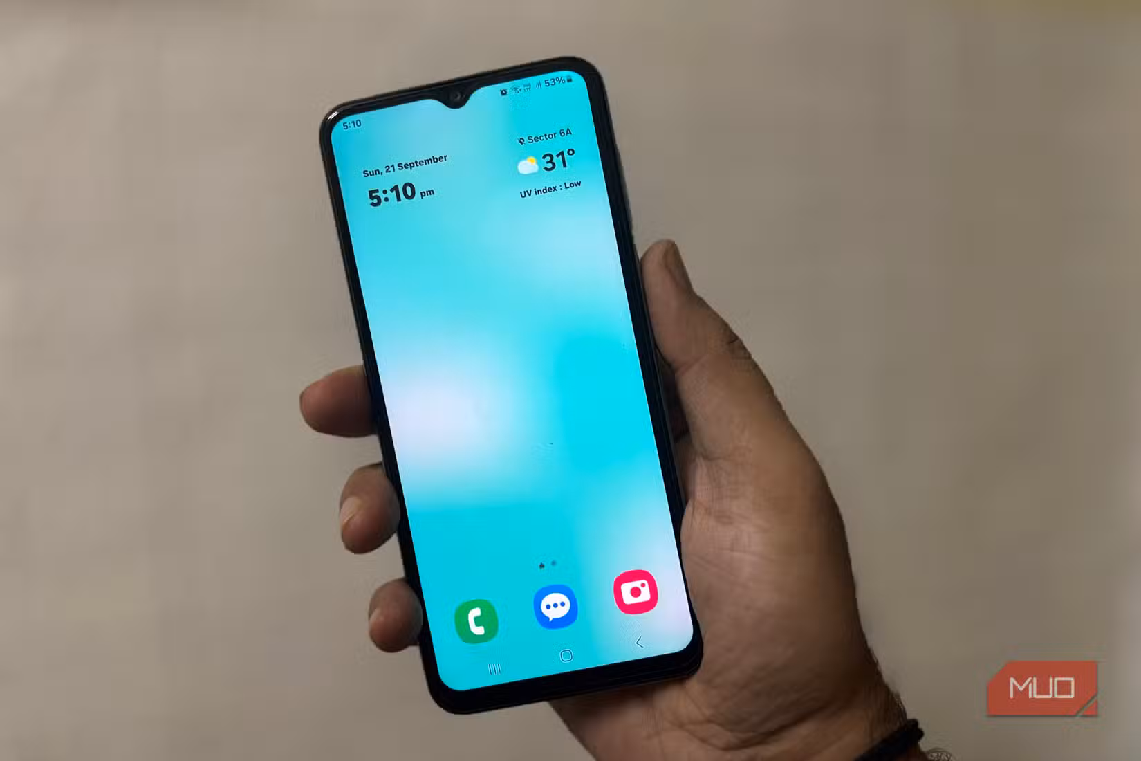 Person holding Samsung phone showing clean home screen with clock and weather