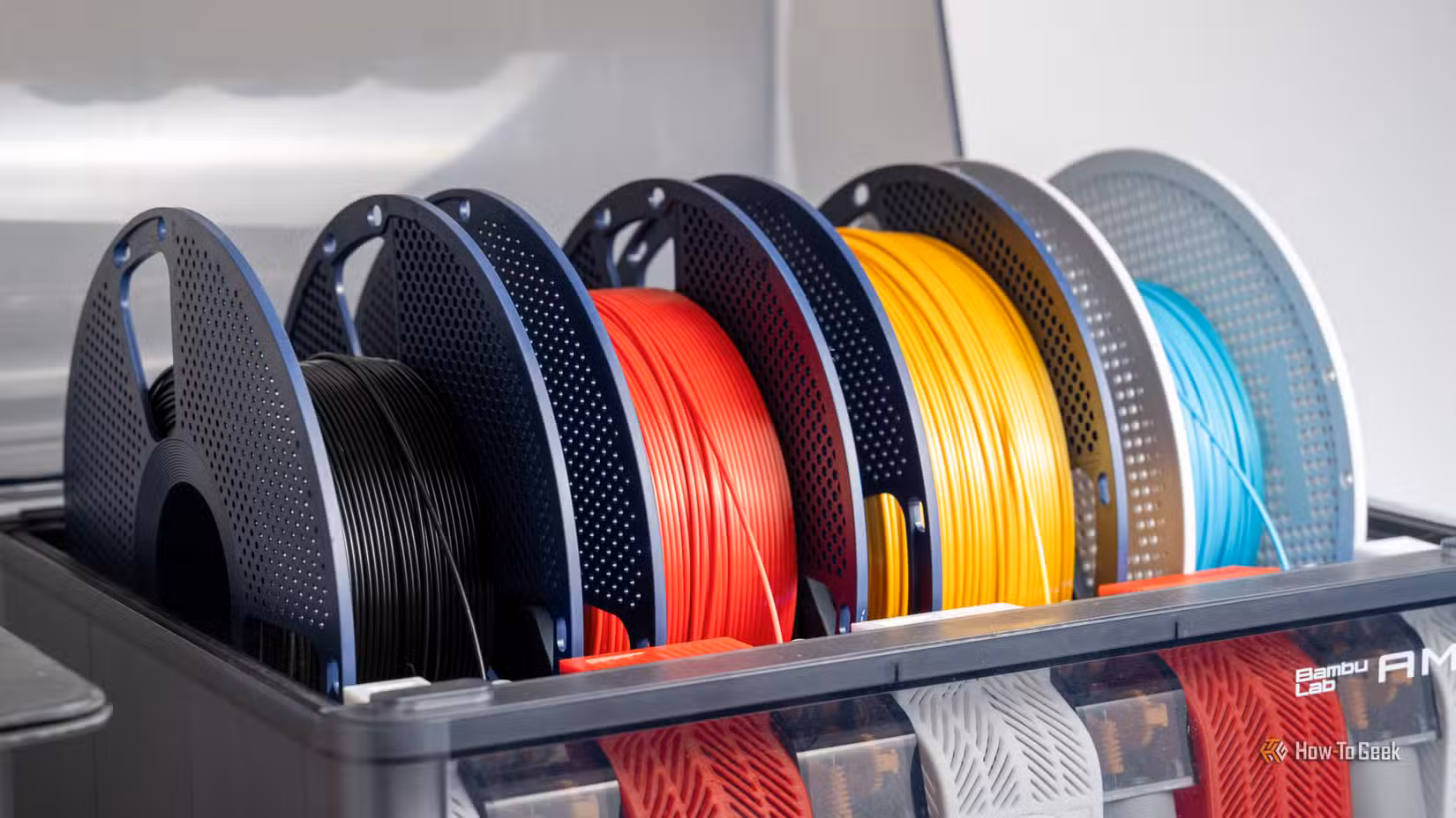 Multiple colorful spools of 3D printer filament loaded inside a Bambu Lab AMS unit.