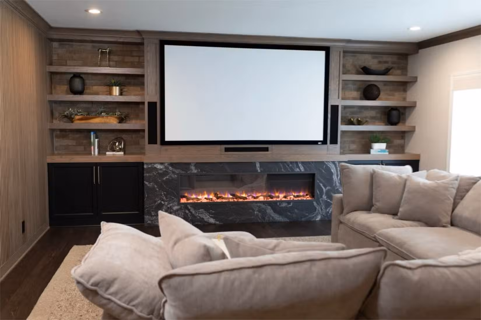 Warm colored home theater setup with the addition of a couch and fireplace.