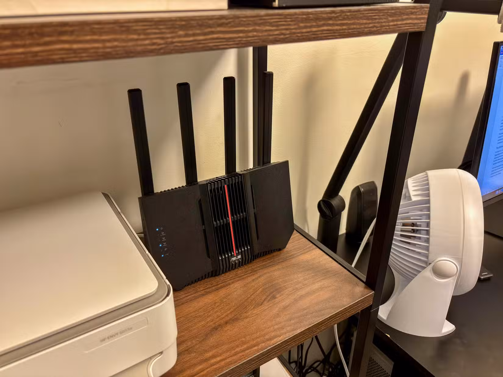 ASUS router on a shelf next to a printer and computer monitor.