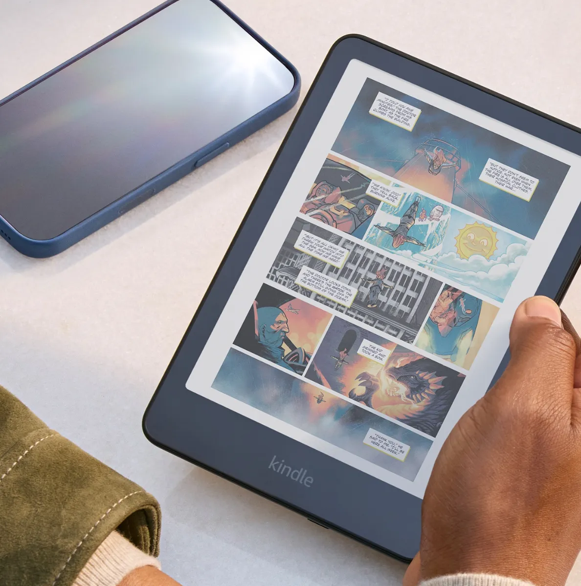 Amazon's Kindle Colorsoft (16GB) being held with a smartphone and sunglasses next to it.