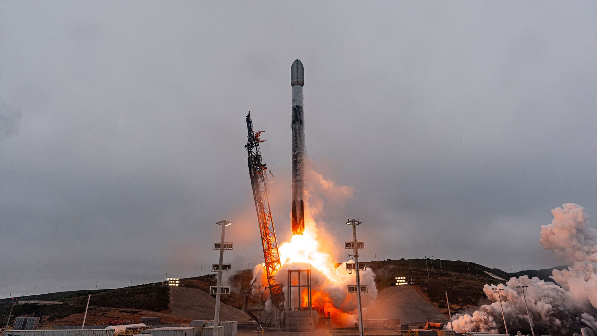a white and black rocket lifts off into overcast cloudy skies