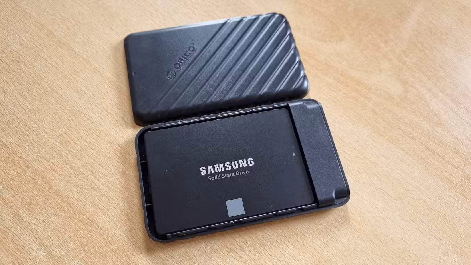 A an opened DIY external SSD showing a Samsung 850 EVO SATA SSD inside it lying on a table.