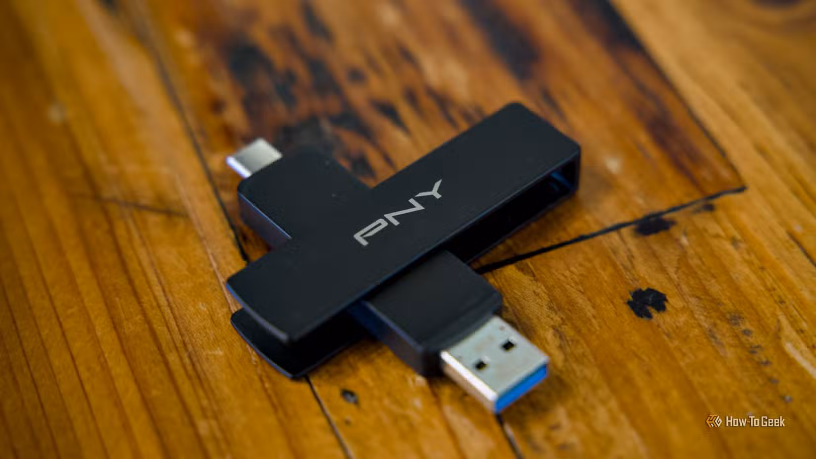 The PNY Duo Link V3 flash drive sitting on a wooden table with both the USB-C and USB-A ports visible.
