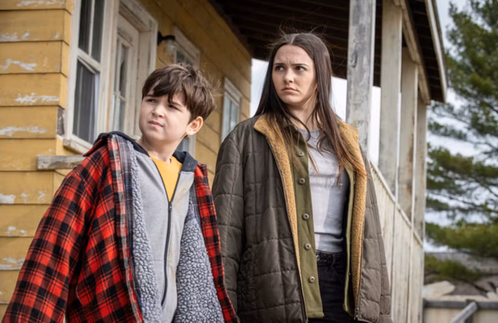 Characters Ethan and Julie alongside a yellow house in From.