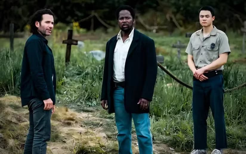 Jim, Boyd, and Kenny stand in a graveyard in From.