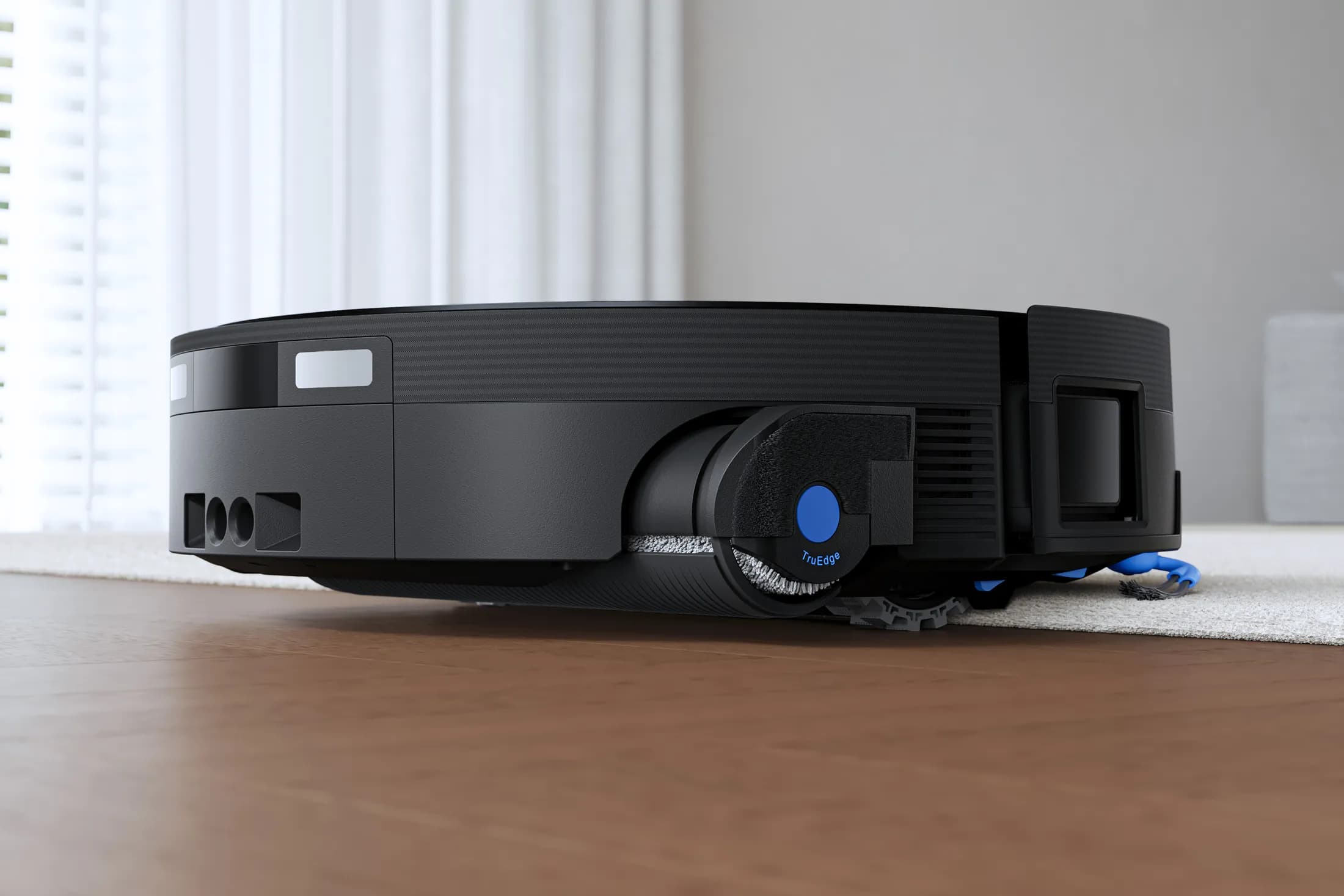 The Ecovacs Deebot X12 OmniCyclone robot vacuum transitioning from hard floors to carpeting.