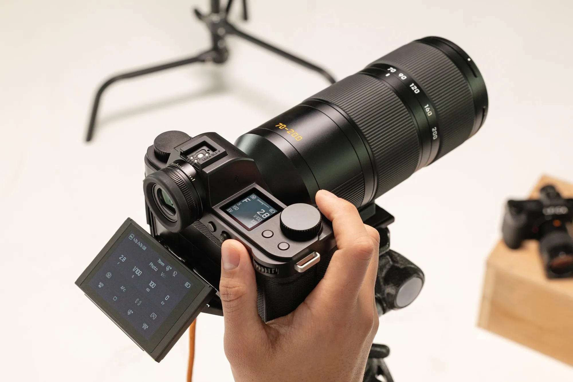 A person holds the Leica SL3-P’s grip while shooting with the camera attached to a tripod.